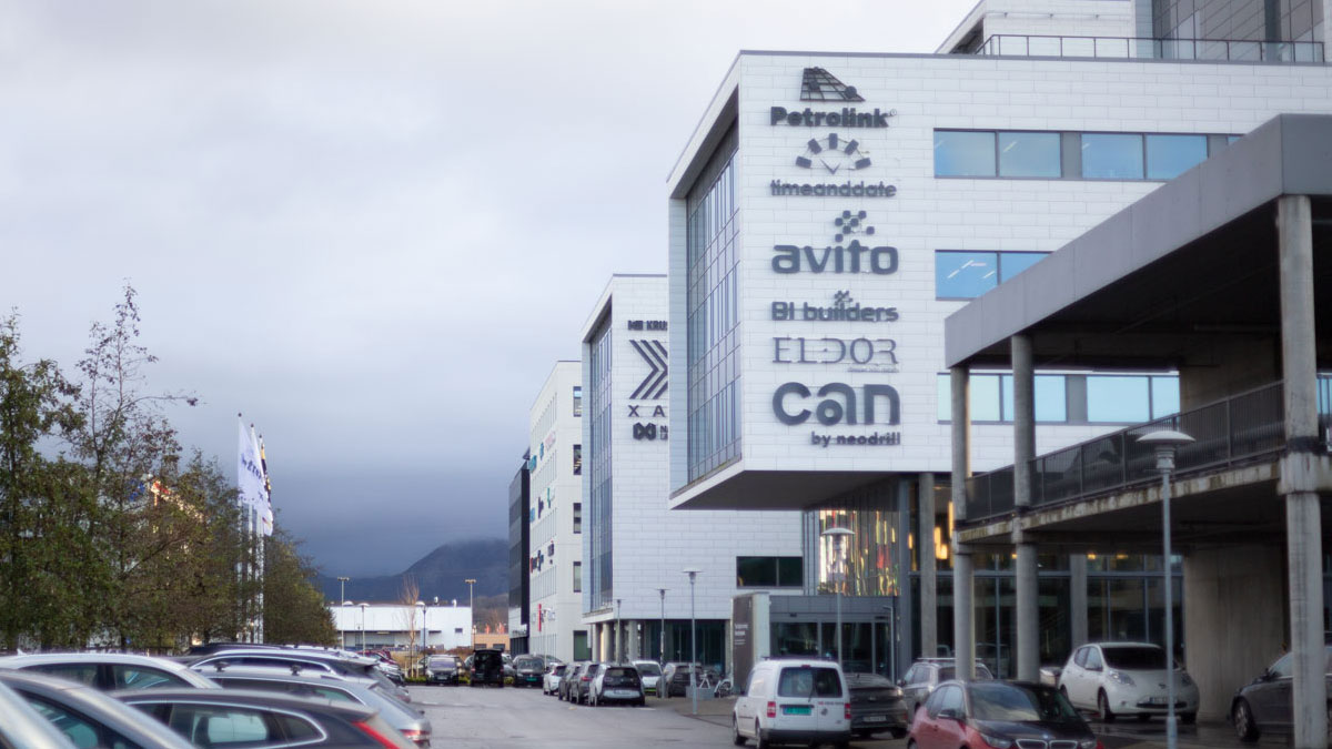 Photo of a grey office building with several company logos, including timeanddate.com. In the background are mountains and grey skies.